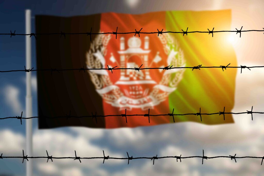 Afghan national flag behind barbed wire symbolizing language barriers and resettlement struggles faced by Afghan refugees worldwide.